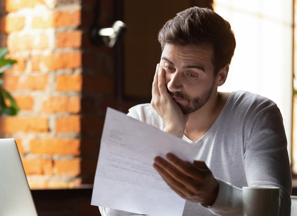 Worried person with chin in his hand reading a document in his other hand