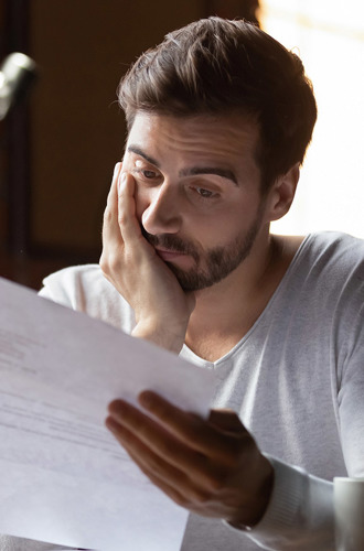Worried person with chin in his hand reading a document in his other hand