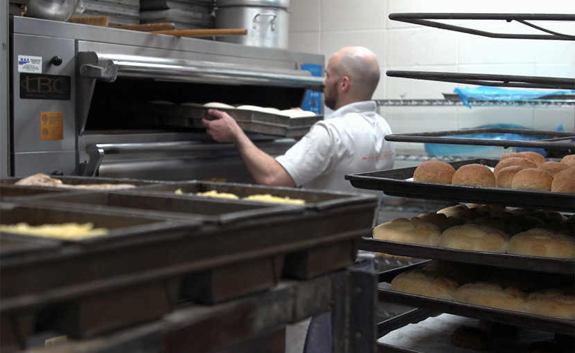 Baker putting a tray of goods into a commercial oven