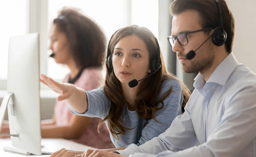 2 people wearing headsets having a discussion in front of a computer
