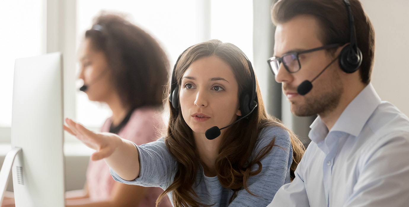 2 people wearing headsets having a discussion in front of a computer