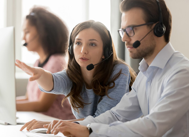2 people wearing headsets having a discussion in front of a computer