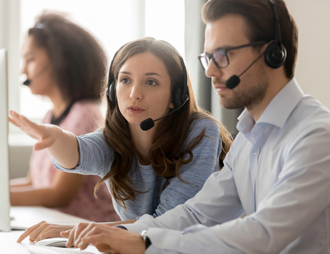 2 people wearing headsets having a discussion in front of a computer
