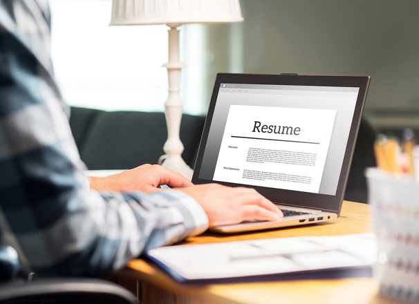 Hands typing on a laptop with the screen showing a resume