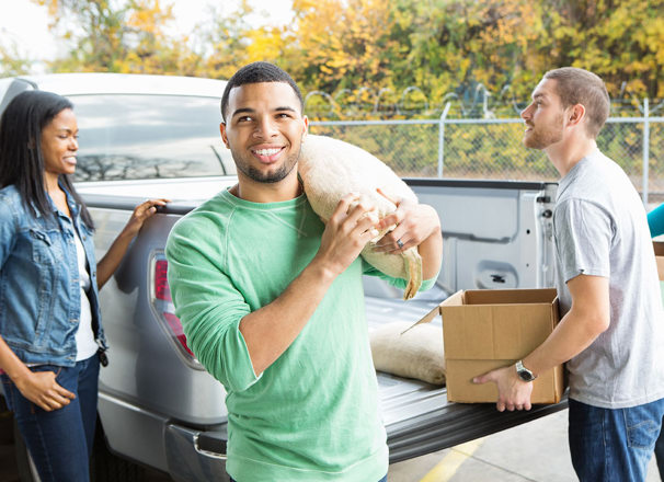 Volunteer carrying a sack of food out of a pickup truck