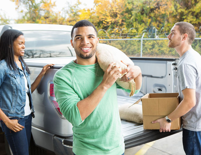 Volunteer carrying a sack of food out of a pickup truck