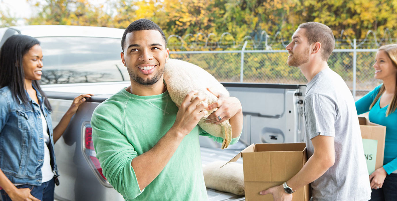 Volunteer carrying a sack of food out of a pickup truck