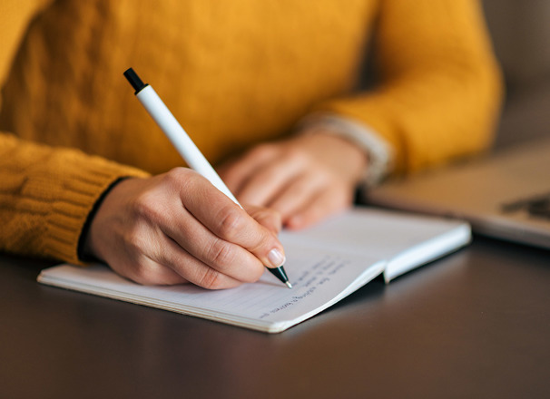 Closeup of person writing in a notebook with a pen