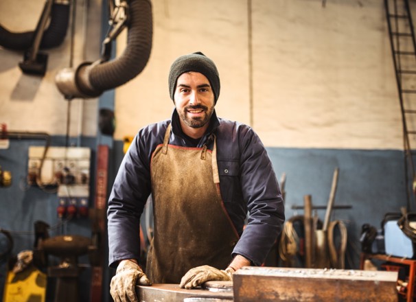 Worker wearing gloves and an apron standing in a workshop