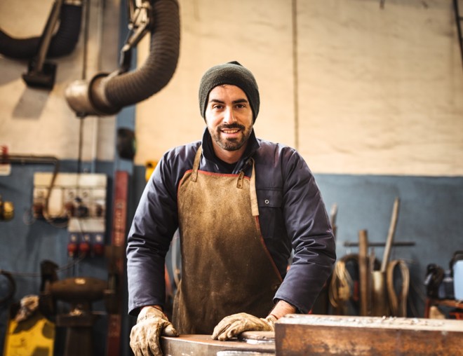 Worker wearing gloves and an apron standing in a workshop