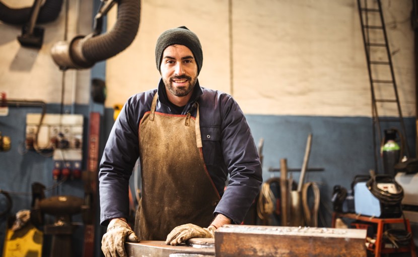 Worker wearing gloves and an apron standing in a workshop