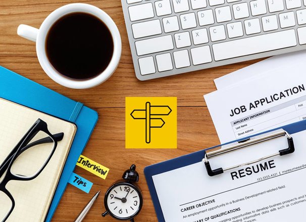 Resume, job application, notebooks, keyboard, coffee and a clock laid out on a desk