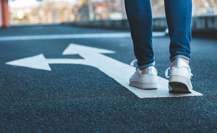 Low perspective of person walking on painted arrows on a road