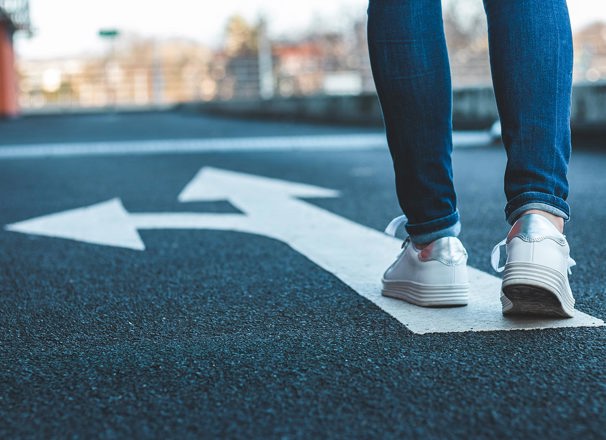 Low perspective of person walking on painted arrows on a road