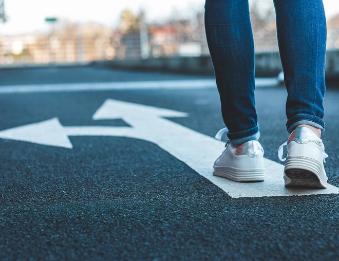 Low perspective of person walking on painted arrows on a road