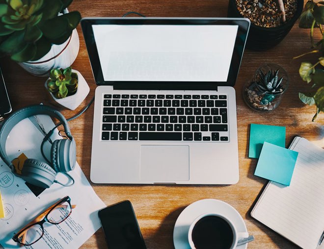 Open laptop with blank screen and other office supplies on a work desk