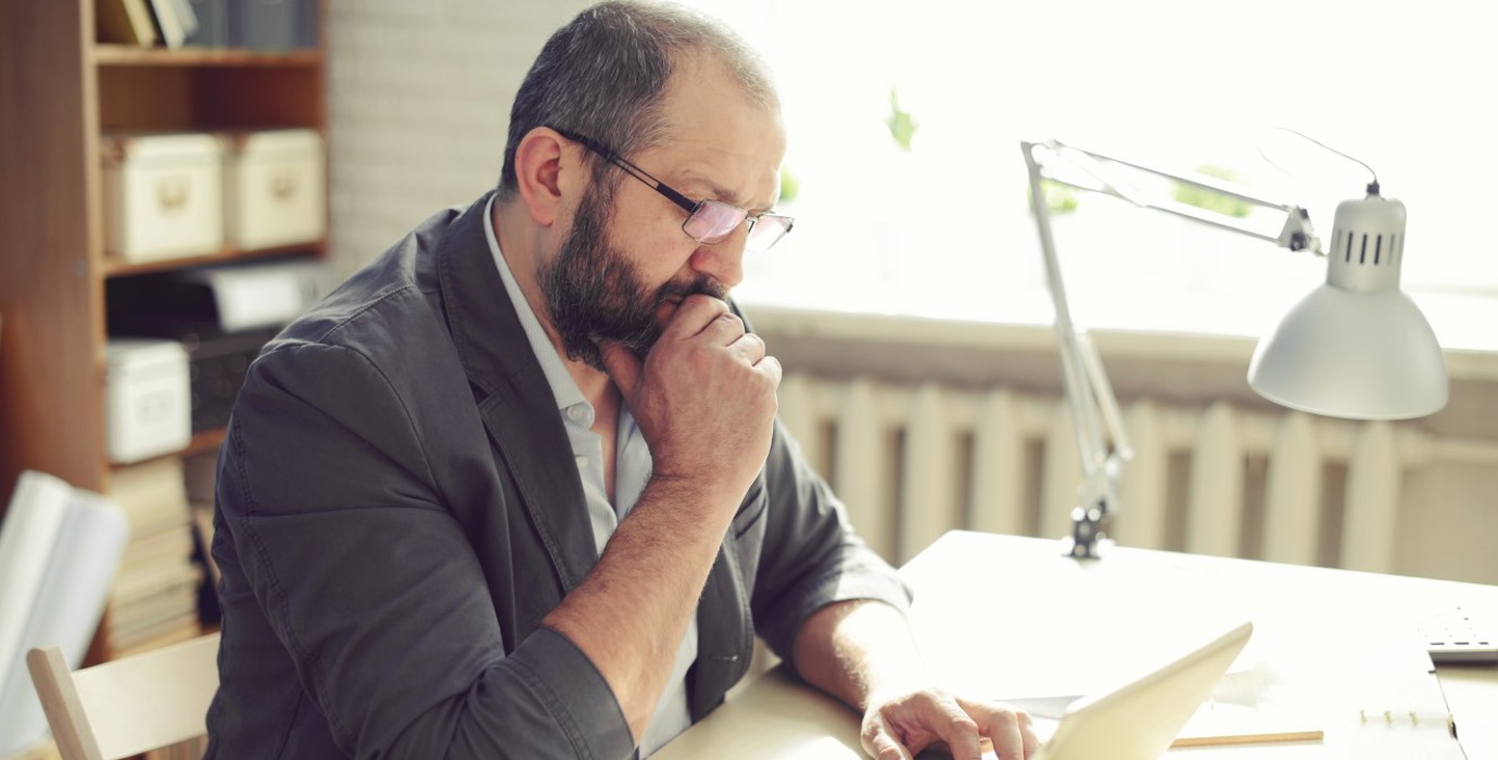 Man thinking while using laptop at his desk