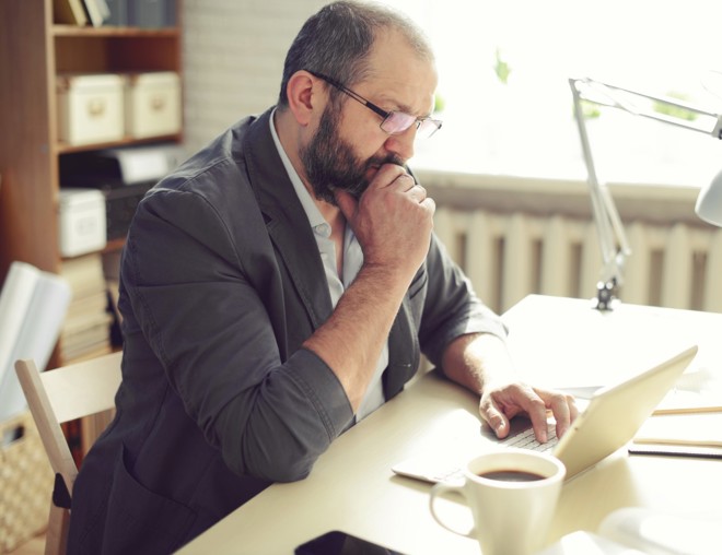Man thinking while using laptop at his desk