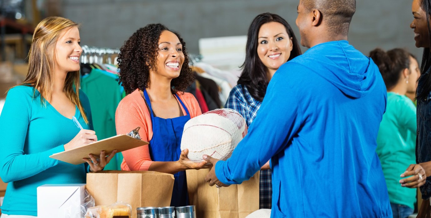 Food bank volunteers sorting food into brown bags.