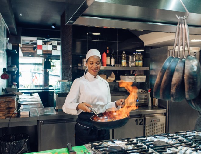 Female chef sauteing in a commercial kitchen.