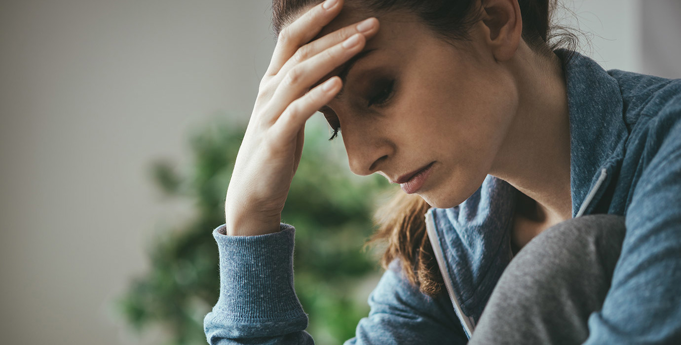 Depressed woman holder her forehead and looking downward.