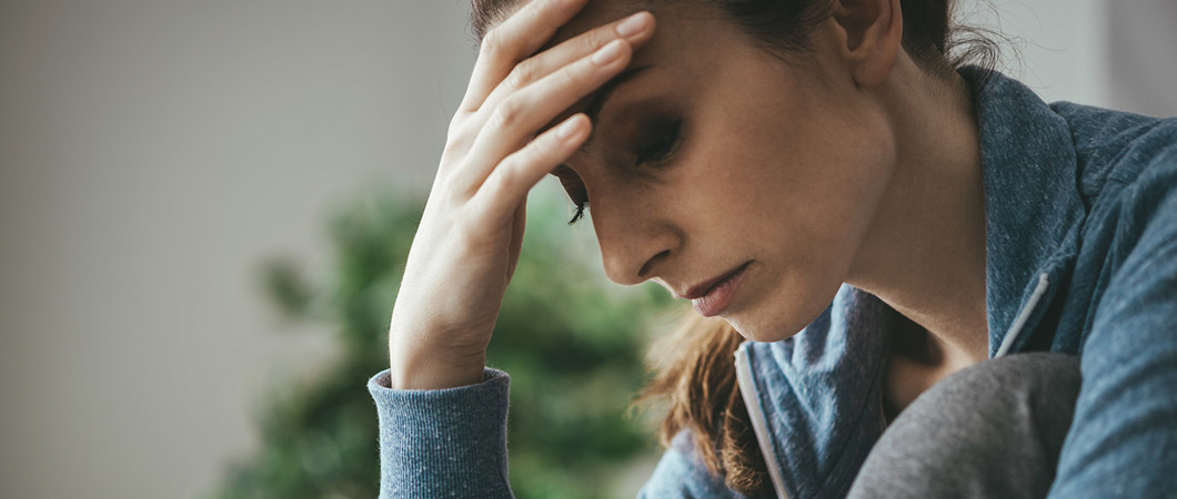 Depressed woman holder her forehead and looking downward.