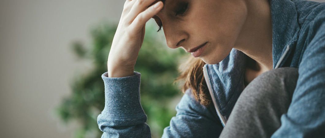 Depressed woman holder her forehead and looking downward.
