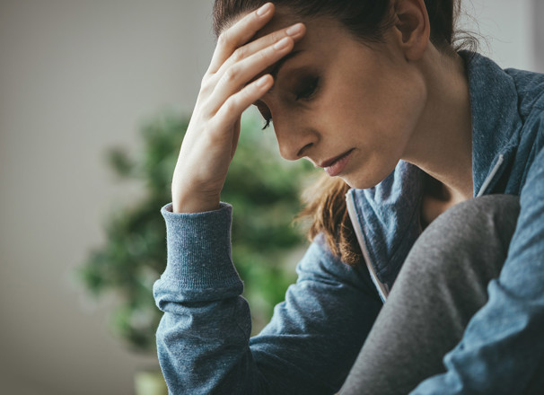 Depressed woman holder her forehead and looking downward.