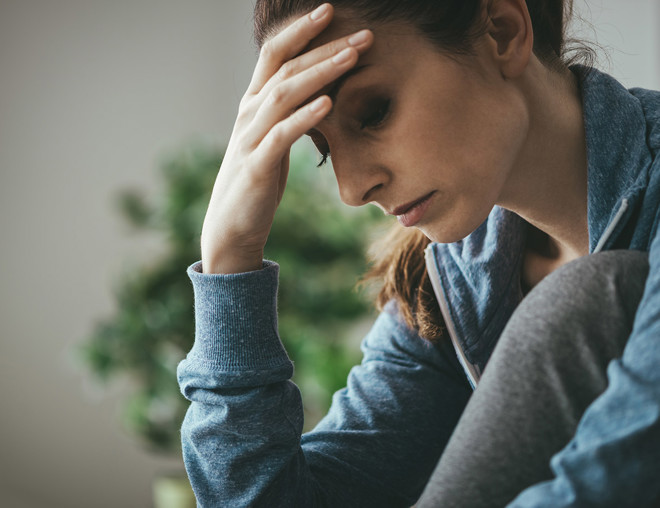 Depressed woman holder her forehead and looking downward.