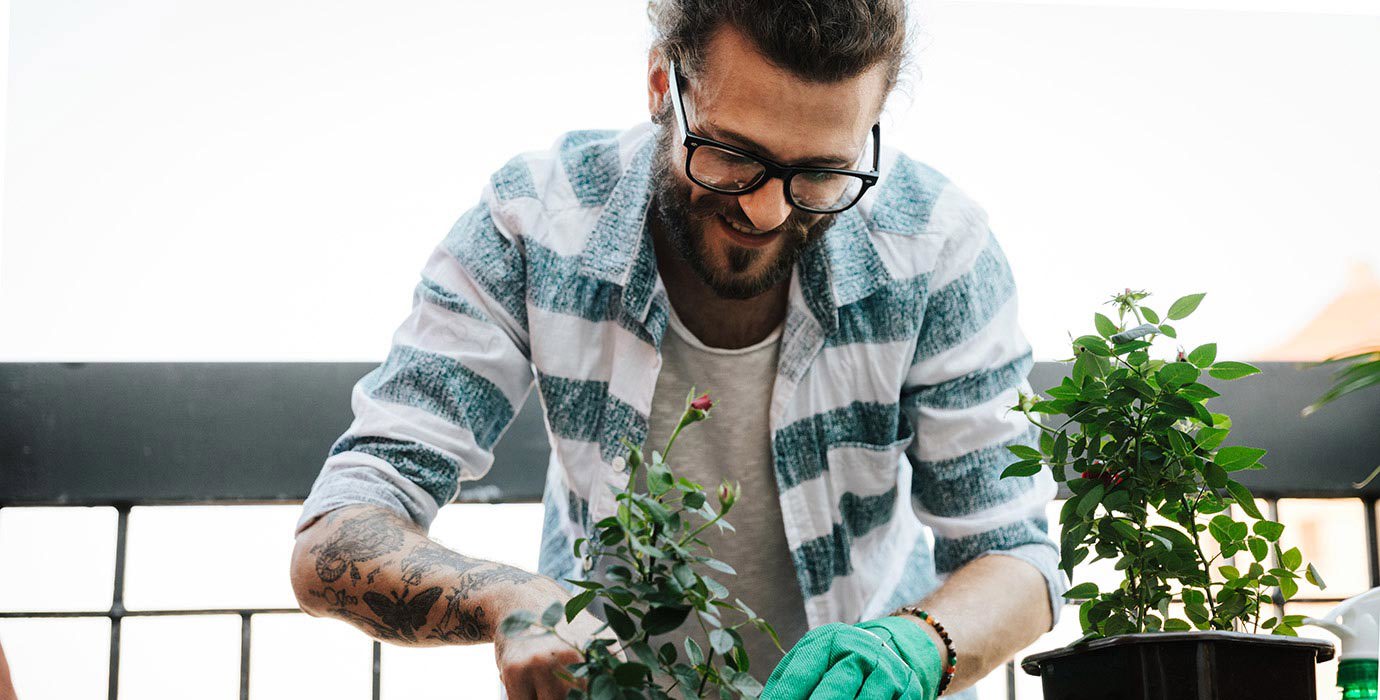 Young man gardening on apartment balcony.