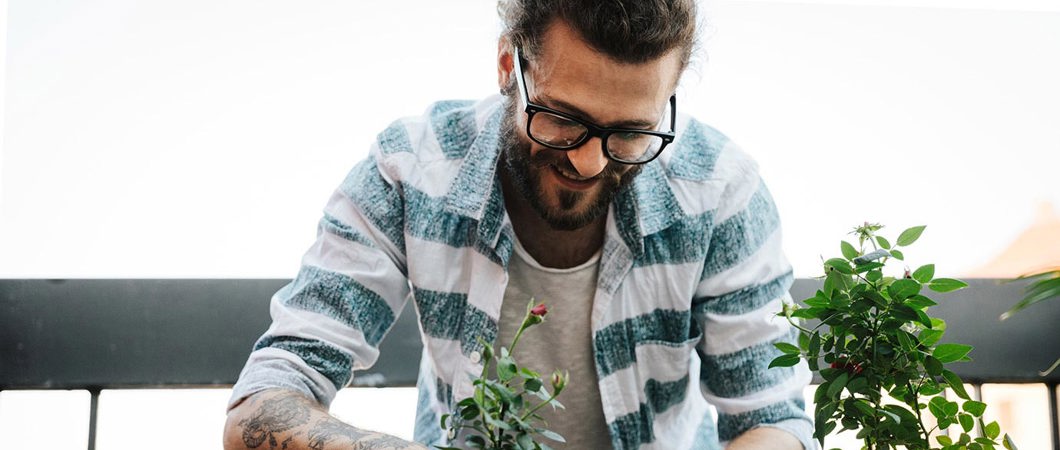 Young man gardening on apartment balcony.