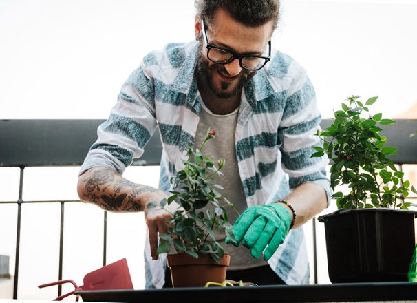 Young man gardening on apartment balcony.