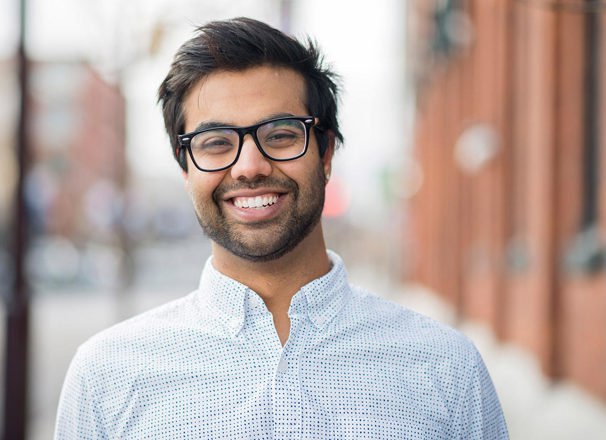 Smiling young man in collared shirt and glasses.