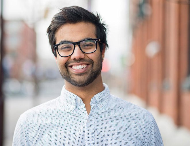 Smiling young man in collared shirt and glasses.