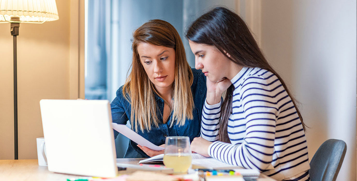 Mother helping her daughter with homework.