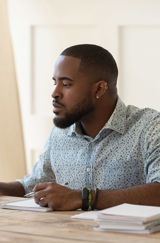 Man working on computer at desk with papers stacked beside him.