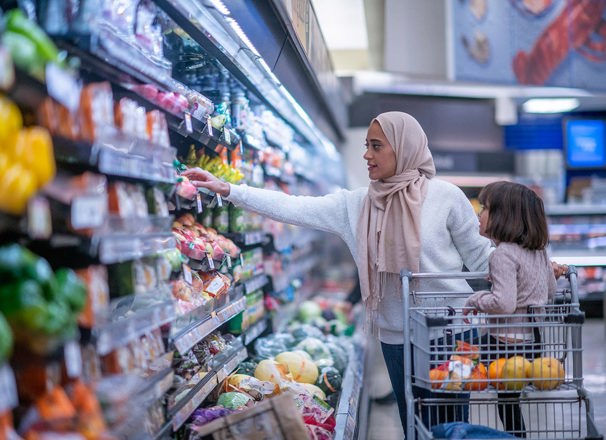 Woman grocery shopping with child in the shopping cart.