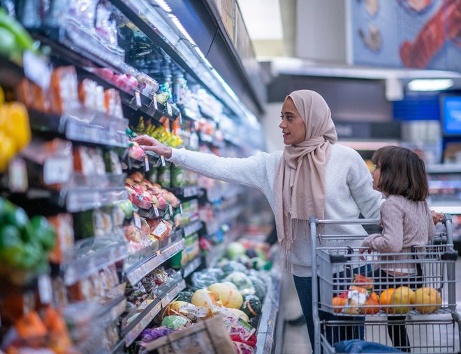 Woman grocery shopping with child in the shopping cart.