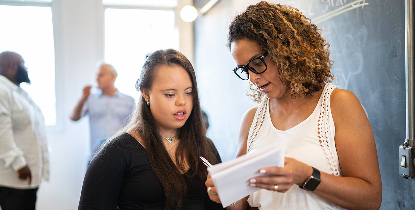 2 people having a discussion and taking notes in a boardroom.