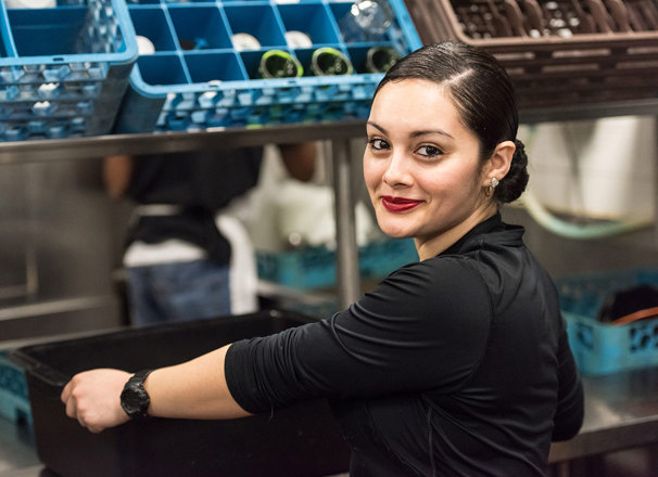 A worker puts a bin of dirty dishes on the counter in a restaurant kitchen.