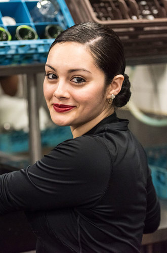A worker puts a bin of dirty dishes on the counter in a restaurant kitchen.