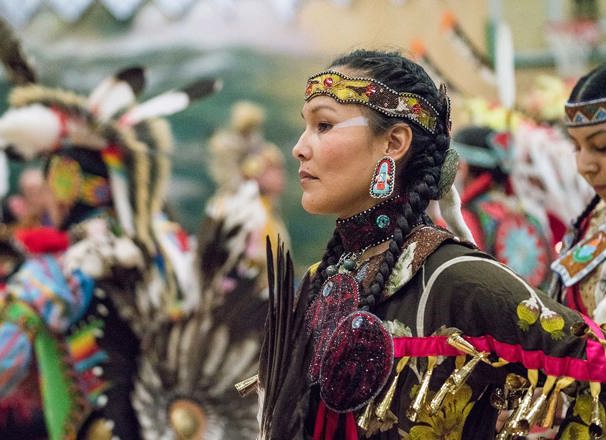 A dancer from Semiahmoo First Nation wearing traditional clothing pauses during a pow wow.