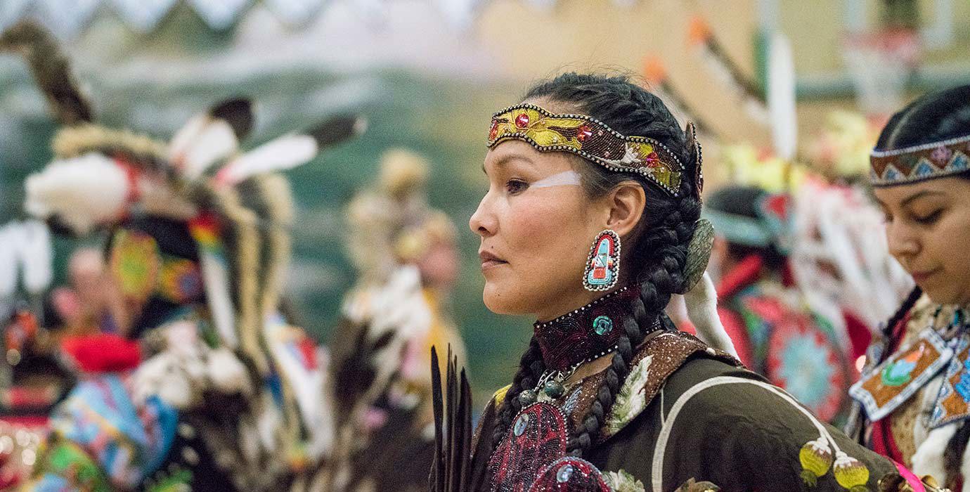 A dancer from Semiahmoo First Nation wearing traditional clothing pauses during a pow wow.