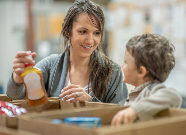 A mother and young child volunteer at a food bank.