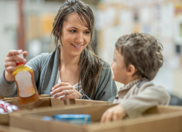 A mother and young child volunteer at a food bank.