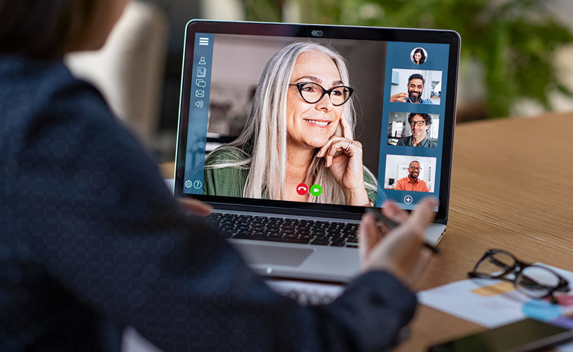 A laptop screen shows a video conference.