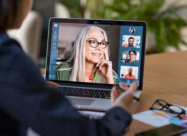A laptop screen shows a video conference.