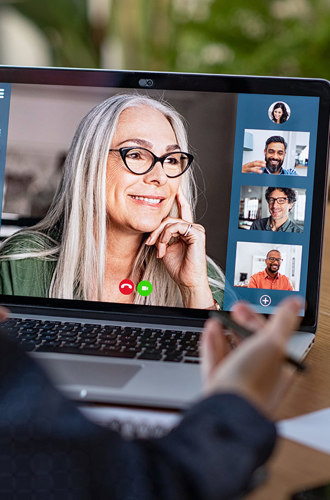A laptop screen shows a video conference.