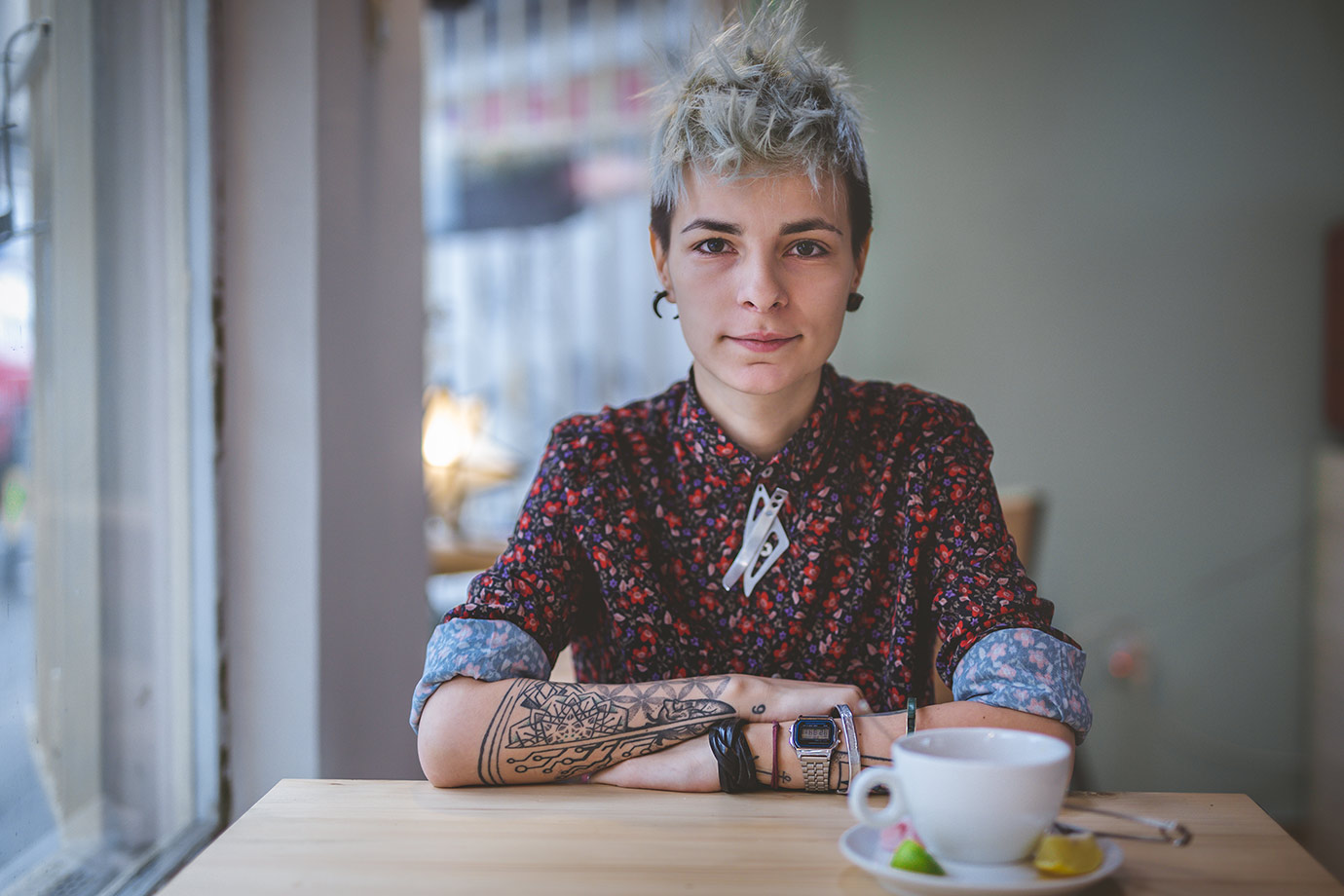 A portrait of a person sitting at a cafe table.