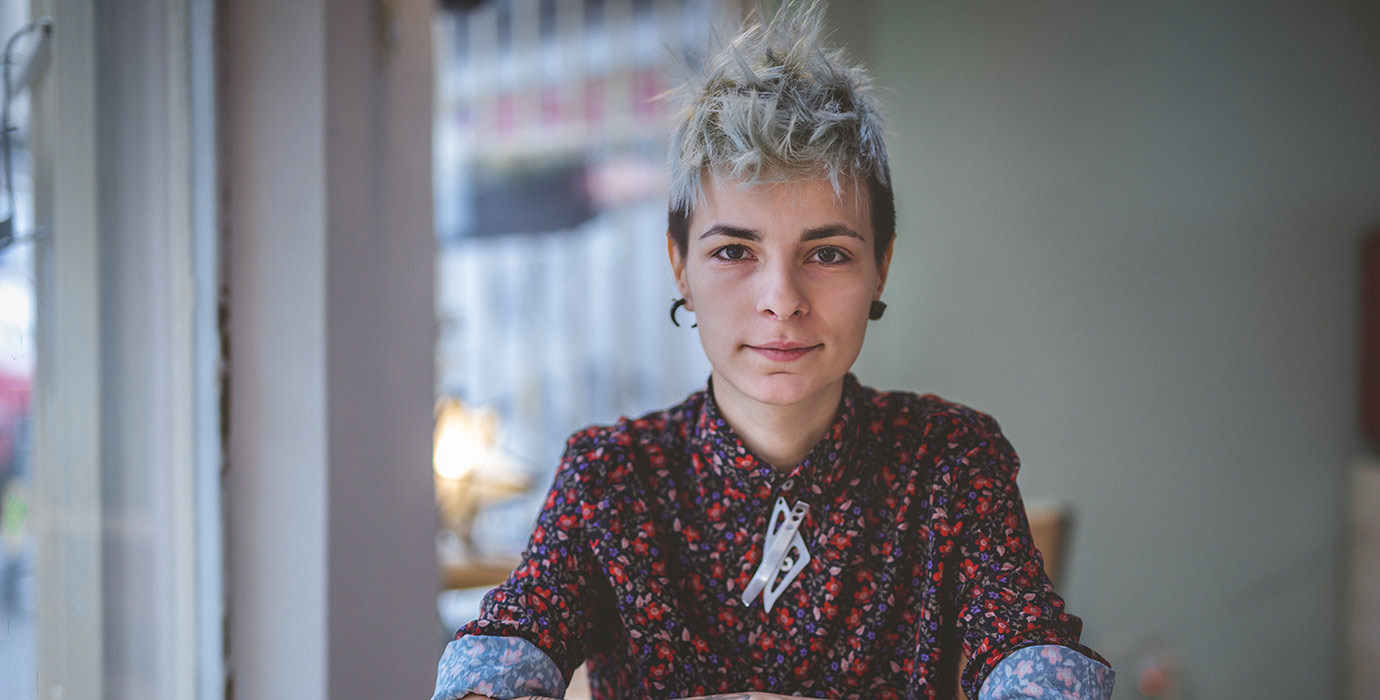 A portrait of a person sitting at a cafe table.